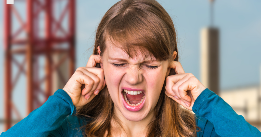 Person protecting ears from loud noise to prevent hearing loss