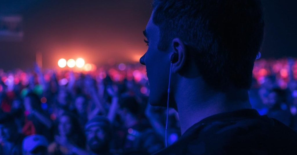 Person using ear protection at a loud event to prevent tinnitus