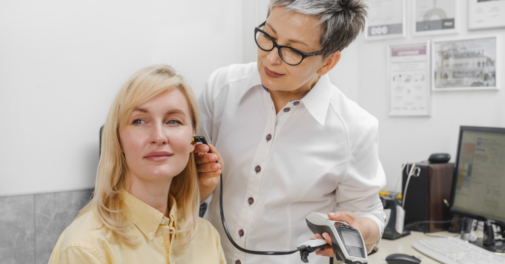 Audiologist performing an OAE test using a small probe in a patient’s ear.