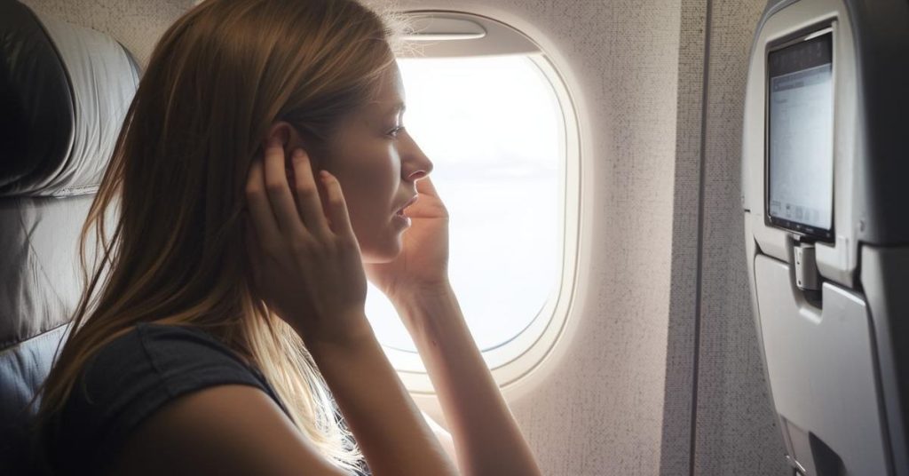 Traveler using techniques to prevent ear pain during a flight.