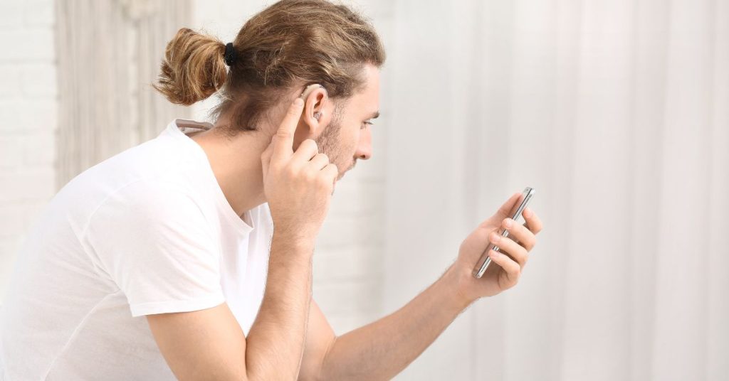 Senior using hearing aids connected to smartphone