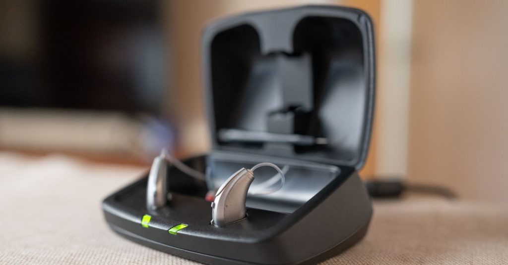 Rechargeable hearing aids in a charging case on a bedside table