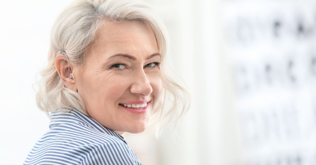 Older adult using hearing aid while consulting an audiologist